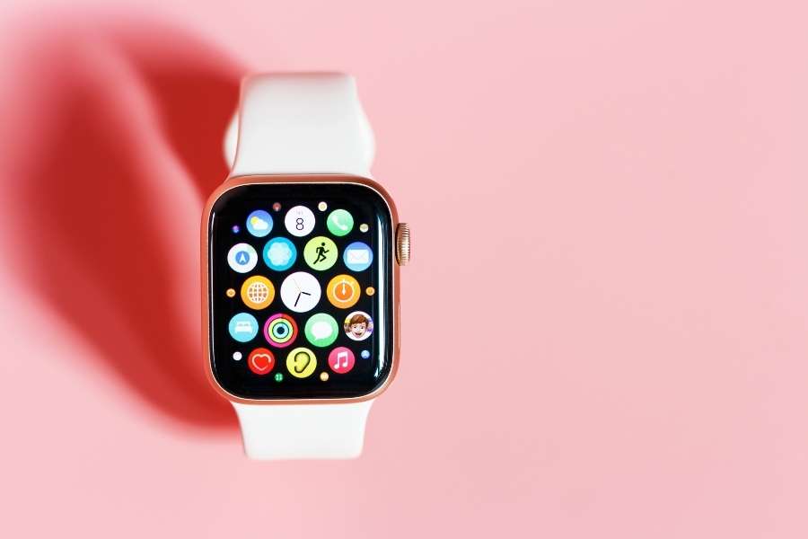 Rose gold wearable fitness technology smartwatch displaying colorful app interface on pink background