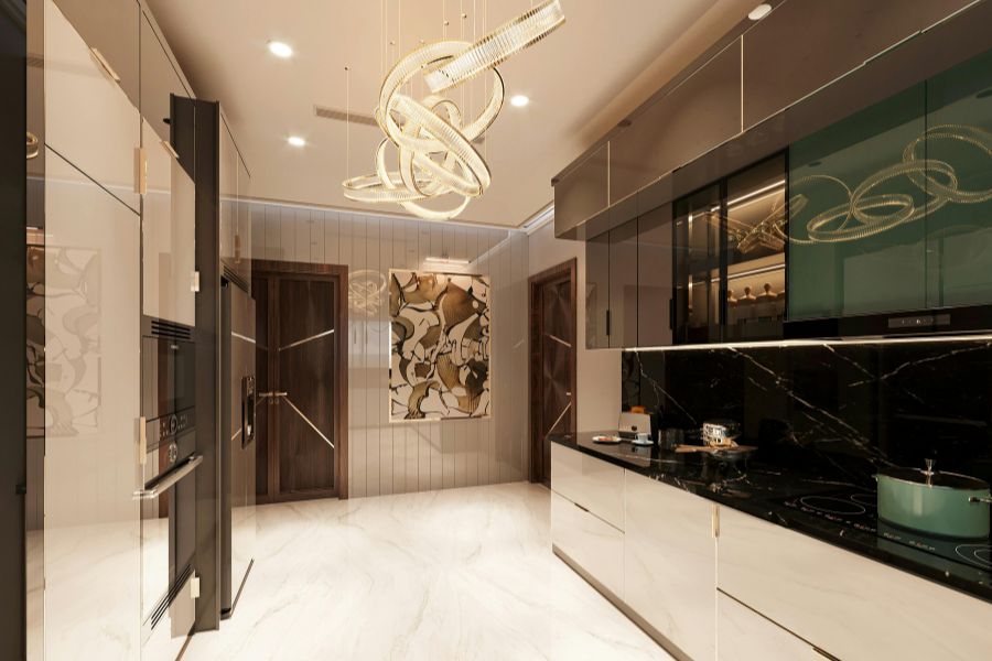 A luxury kitchen with a sculptural gold ring chandelier as a bold kitchen lighting statement above white marble floors and dark cabinetry.
