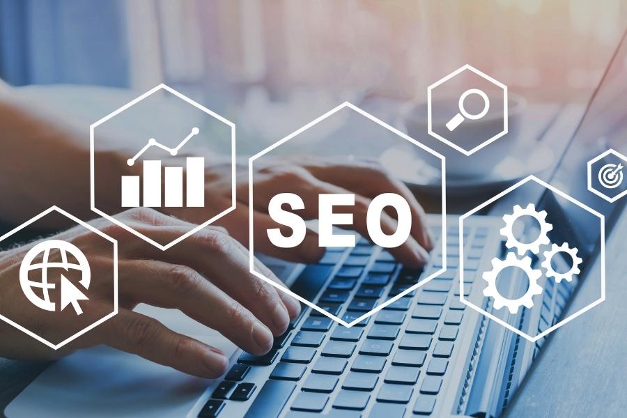 Hands typing on a laptop keyboard with digital SEO marketing icons overlaid on the screen.